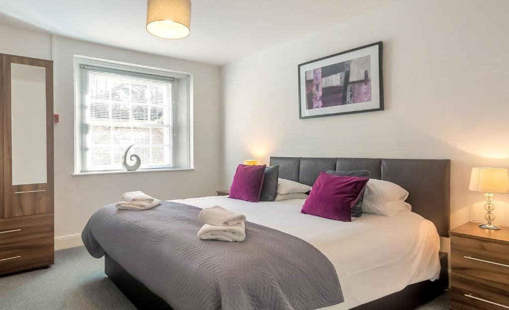 a bedroom with a large bed with purple pillows at Self contained, Garden Flat, Montpellier Villas in Cheltenham