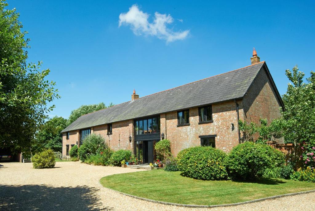 a large brick building with a black roof at Hilltop Barn in Blandford Forum