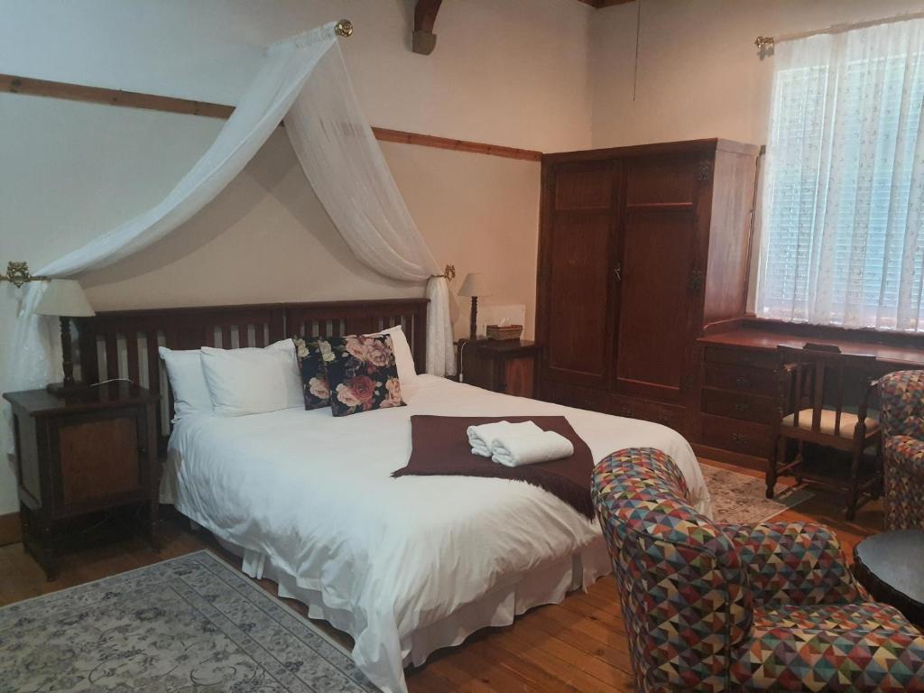 a bedroom with a large bed and a chair at Lord Fraser Guest House in Wepener