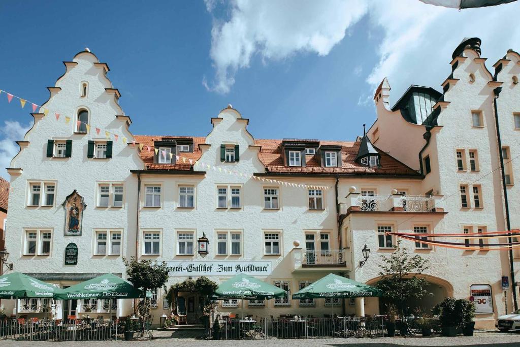 a large white building with green umbrellas in front of it at Brauereigasthof zum Kuchlbauer in Abensberg