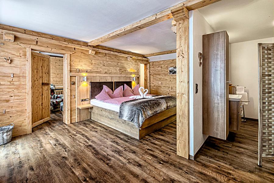 Schlafzimmer mit Holzwänden und einem Bett mit rosa Kissen in der Unterkunft Almhotel Grünsteinblick in Königssee