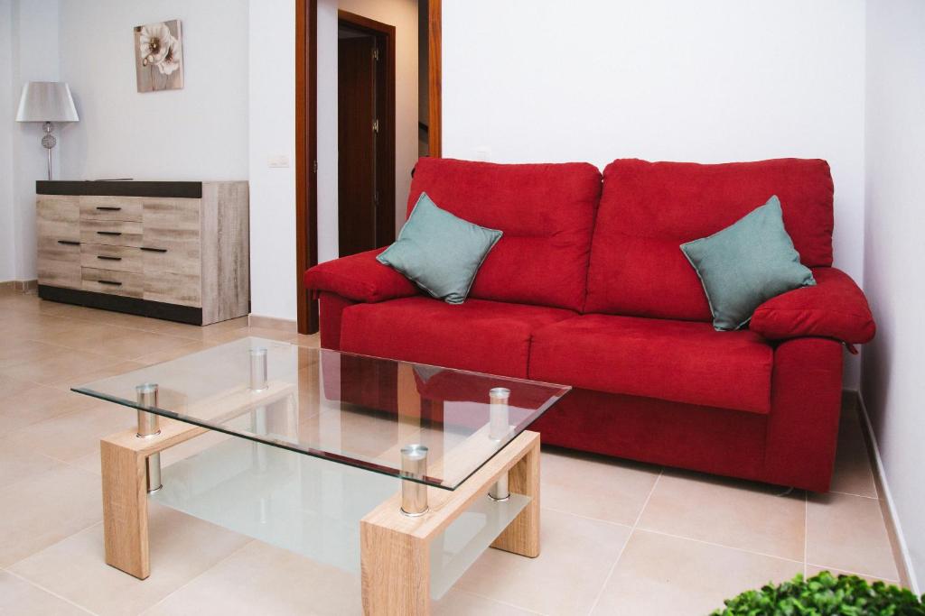 sala de estar con sofá rojo y mesa de cristal en LA CASITA DE BAUTISTA 2 llaves montanchez -caceres, en Montánchez