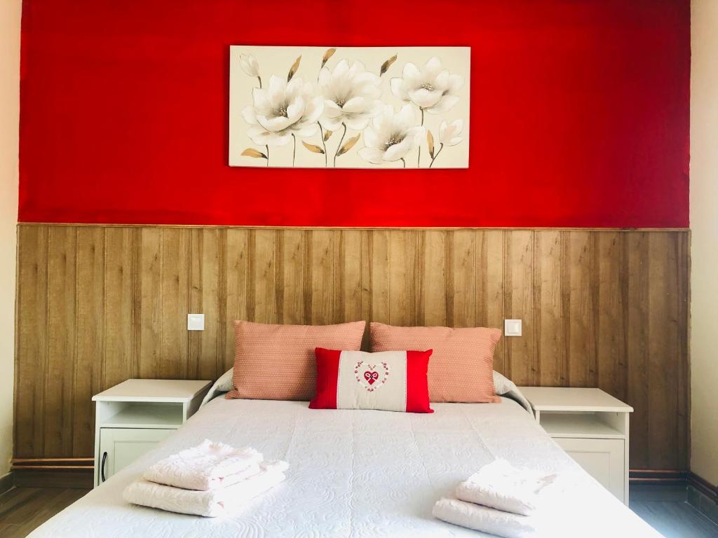 1 dormitorio con cama blanca y pared roja en Casa El Tejar, en Las Navas del Marqués