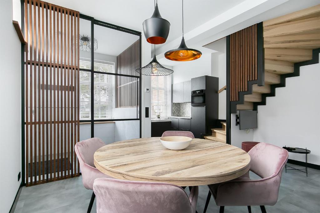 a dining room with a wooden table and pink chairs at Hello Zeeland - Appartement Weststraat 36 in Domburg