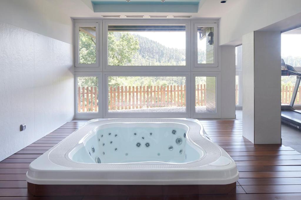a bath tub in a room with a large window at Hotel Txoriene - Arrieta - HBI01298 in Arrieta