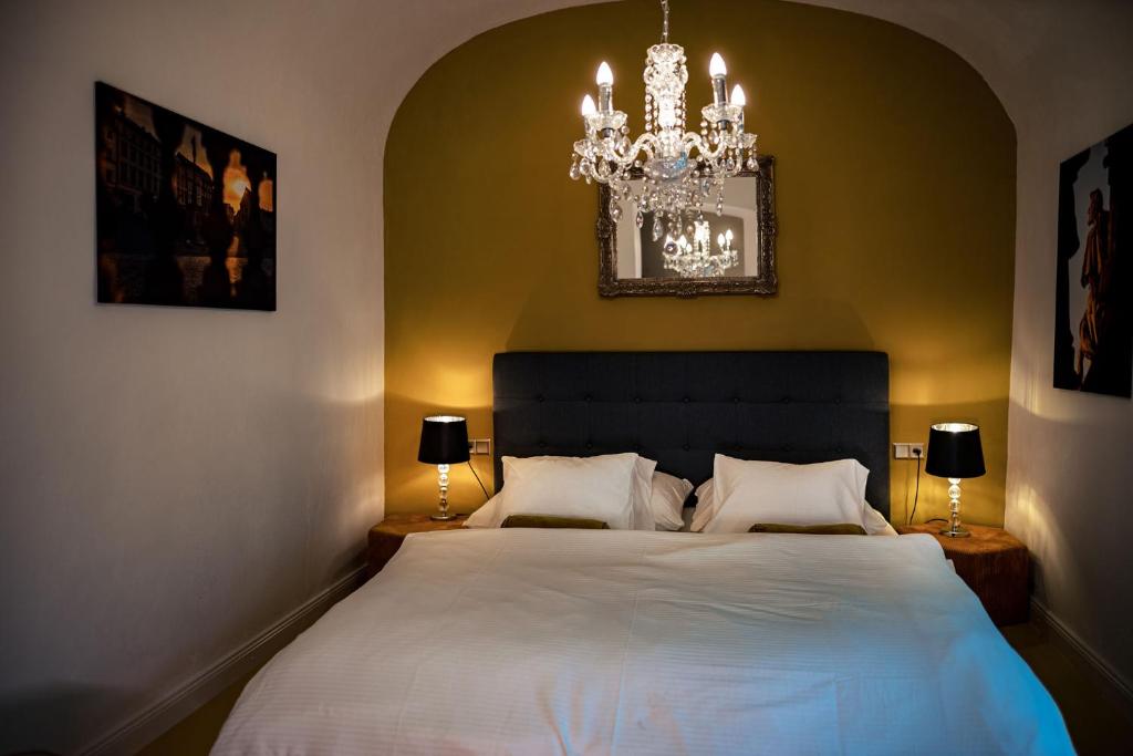 a bedroom with a large white bed with a chandelier at Silvie Apartments - Blažejský in Olomouc