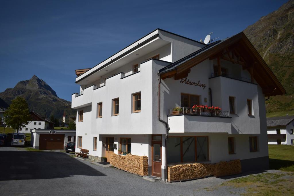 un edificio blanco con un balcón con flores rojas. en Adamsberg, en Galtür