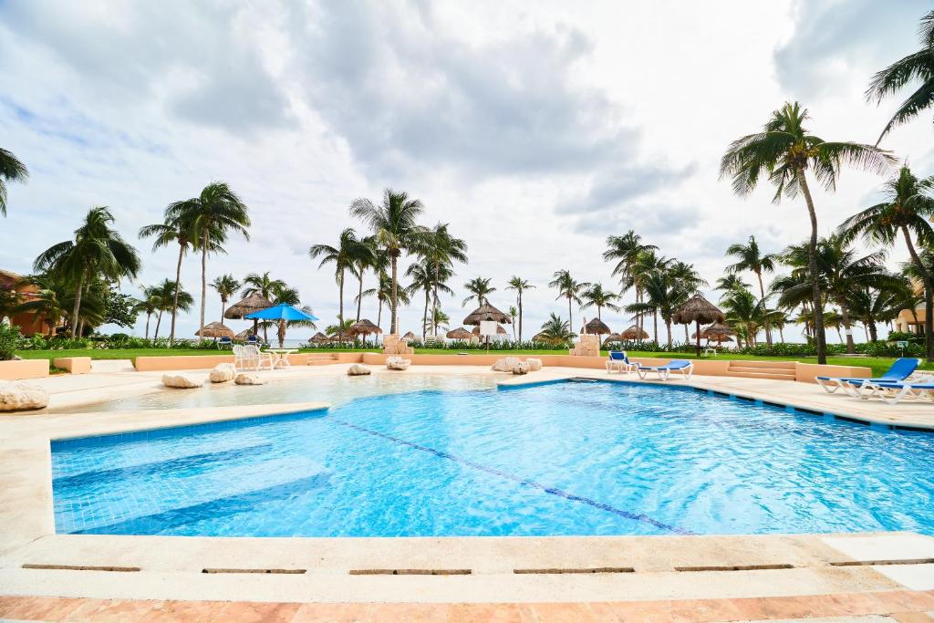 a pool at a resort with palm trees at Peaceful & Rustic Apartment Beachfront, Swimming Pool & Terrace Awesome Amenities in Puerto Aventuras