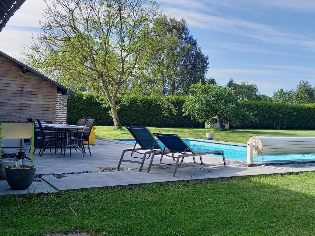 d'une terrasse avec des chaises et une table à côté de la piscine. dans l'établissement Aux p'tits bonheurs la grange, à Neuve-Chapelle