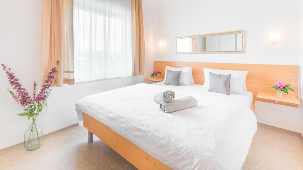 - une chambre avec un grand lit blanc et une serviette dans l'établissement Haus Familie Presslauer-Mori, à Klopein am Klopeiner See