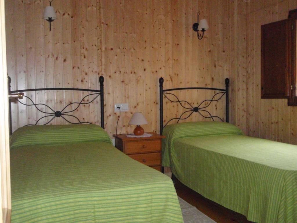 2 Betten in einem Zimmer mit grüner Bettwäsche in der Unterkunft Casa para vacaciones junto al Parque de la Naturaleza de Cabarceno in Obregón