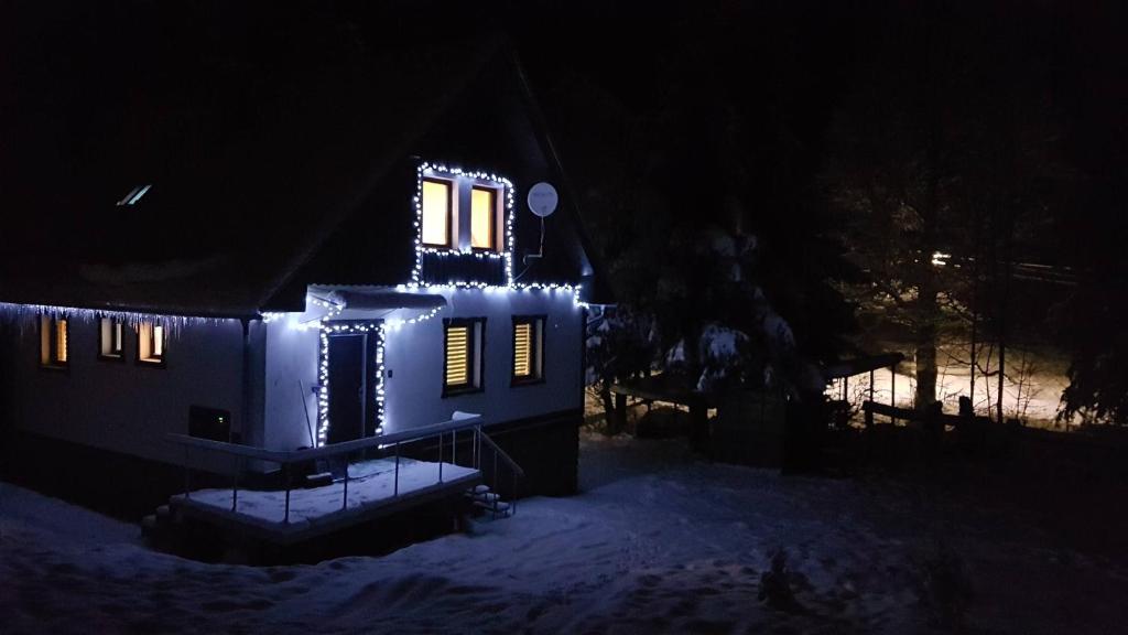a house with lights on it in the snow at night at Chata Tanvaldský Špičák in Tanvald