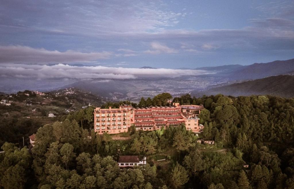 un grand bâtiment au sommet d'une colline plantée d'arbres dans l'établissement Club Himalaya, by ACE Hotels, à Nagarkot