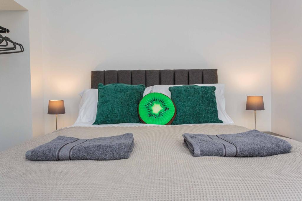 ein Bett mit grünen Kissen und einem grünen Frisbee drauf in der Unterkunft Cherry Property - Kiwi Suite in Blackpool