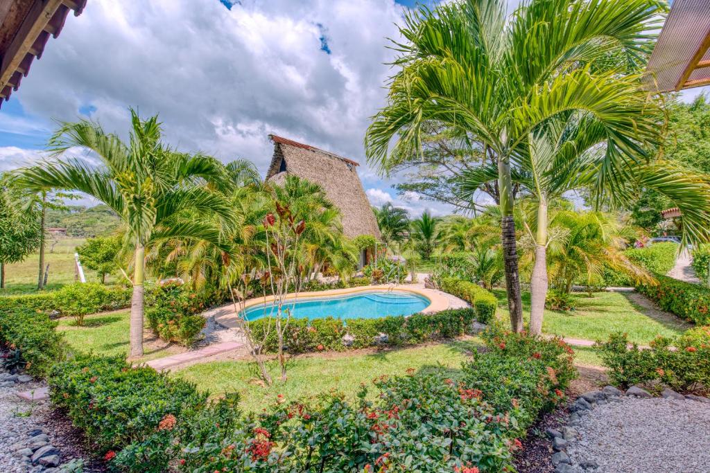 an exterior view of a resort with a swimming pool and palm trees at Hotel Villas Tangerine in Sámara