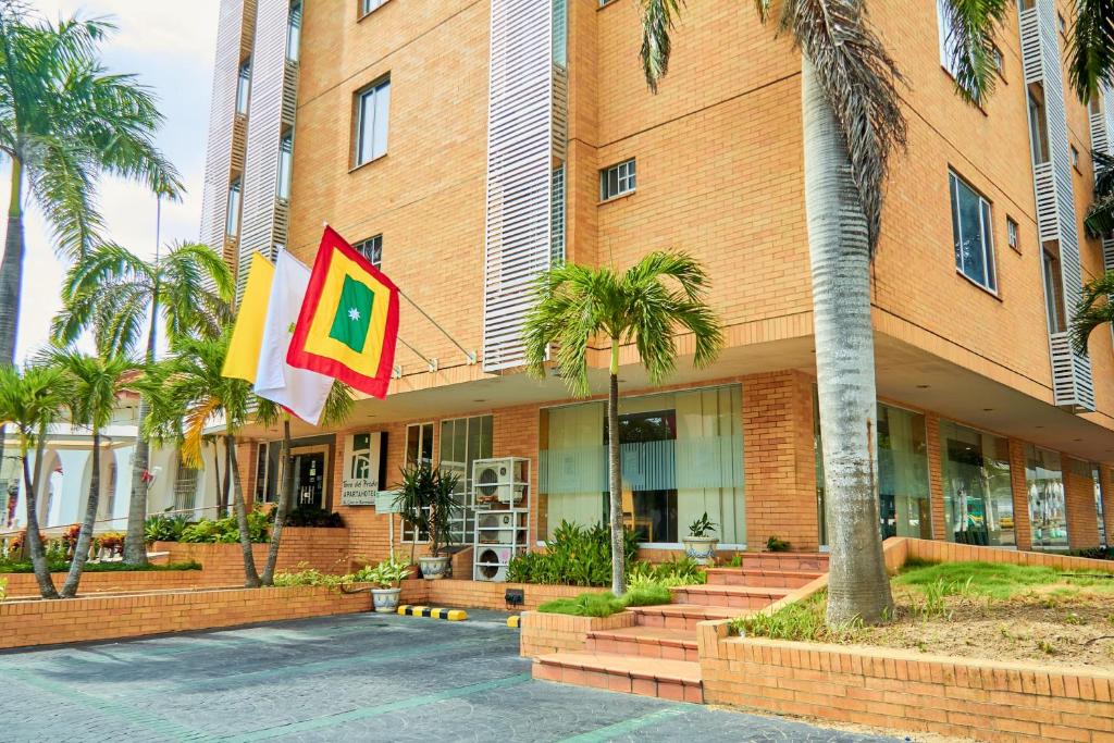 um edifício com palmeiras e bandeiras em frente em Hotel Torre del Prado em Barranquilla