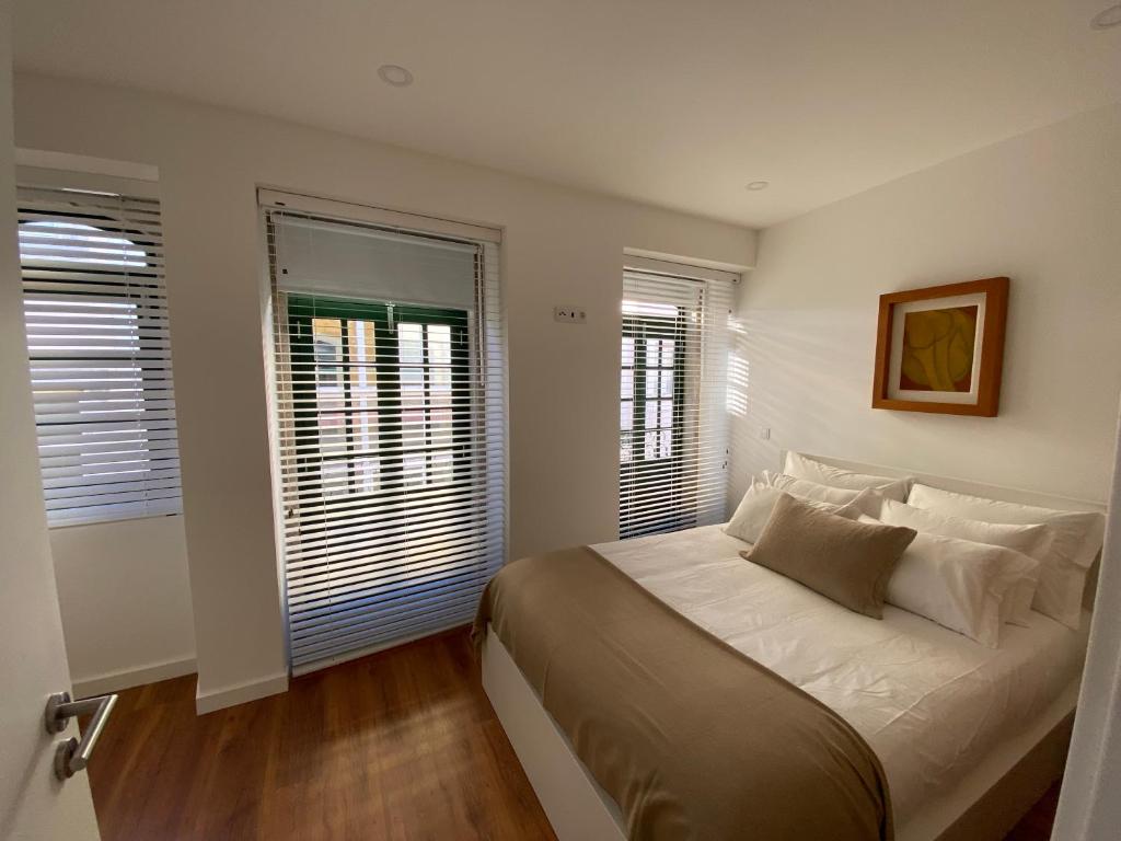 a bedroom with a large bed and two windows at Casa Torta in Setúbal