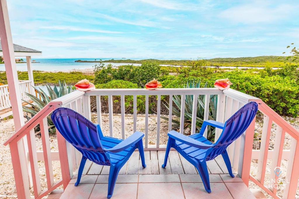 two blue chairs sitting on a porch with the beach at Chalk Sound Beach Residences Near Sapodilla Bay Beach by Angel Host in Providenciales