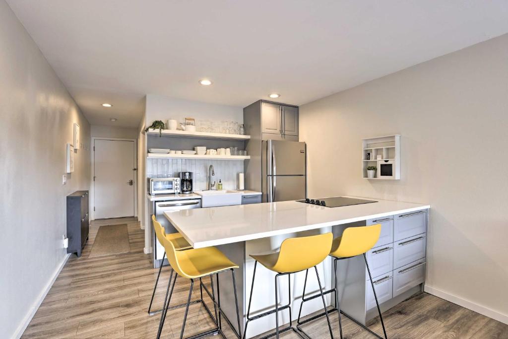 a kitchen with a counter and yellow bar stools at Modern Frisco Studio Walk to Main Street! in Frisco