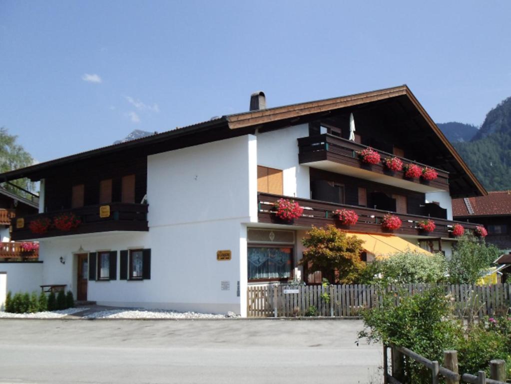 ein weißes Gebäude mit roten Blumen auf den Balkonen in der Unterkunft Gästehaus Drahrer - Chiemgau Karte in Inzell