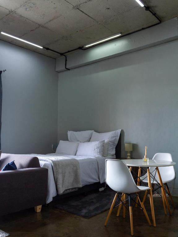 a bedroom with a bed and a table and a couch at Lux Studio Apartment @ Hallmark House in Johannesburg