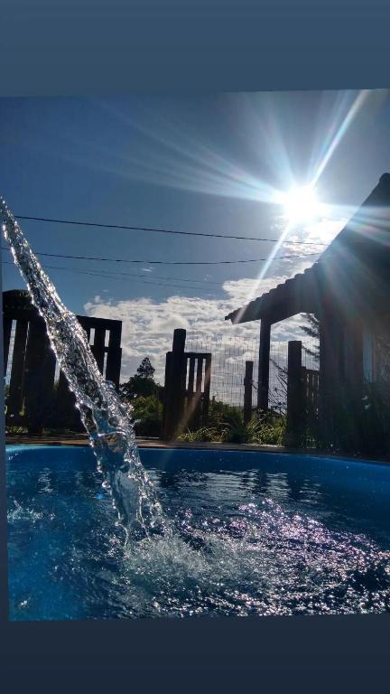 a person is pouring water into a swimming pool at Chalés Praia do Rosa piscina compartilhada in Imbituba