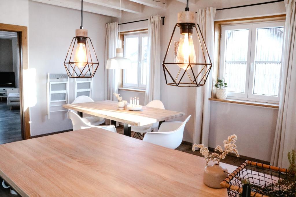 a dining room with a table and chairs and lights at FLYGGE Apartments in Altusried