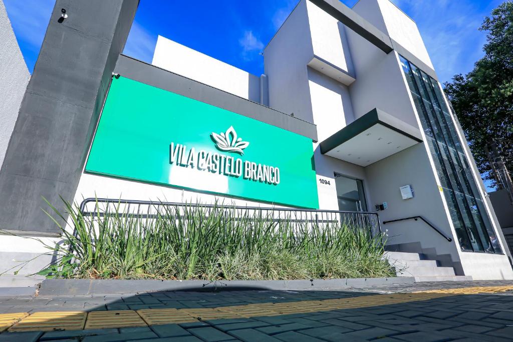 a building with a green sign in front of it at Vila Castelo Residencial no Centro de Foz in Foz do Iguaçu