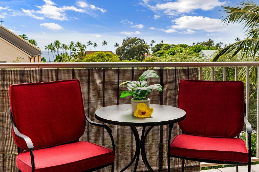 two red chairs and a table on a balcony at Kailua Village#307 in Kailua-Kona