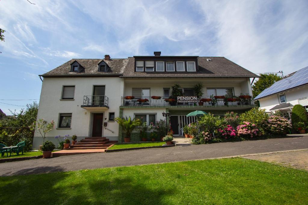 une grande maison blanche avec des fleurs devant elle dans l'établissement Ferienwohnung Moselnest, à Piesport