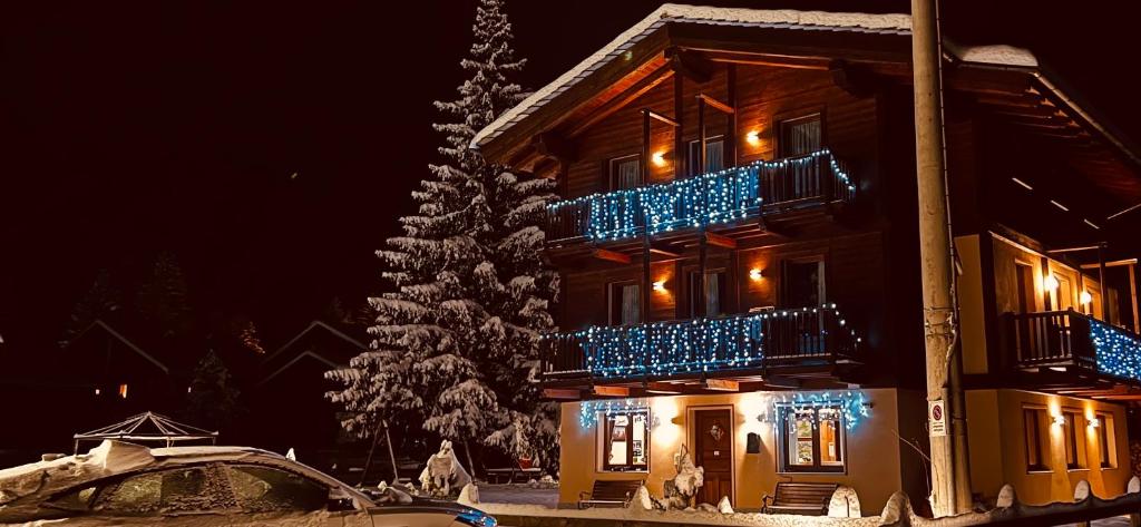 a christmas tree in front of a house with blue lights at Villa Americana Chambres d'Hotes in Champoluc