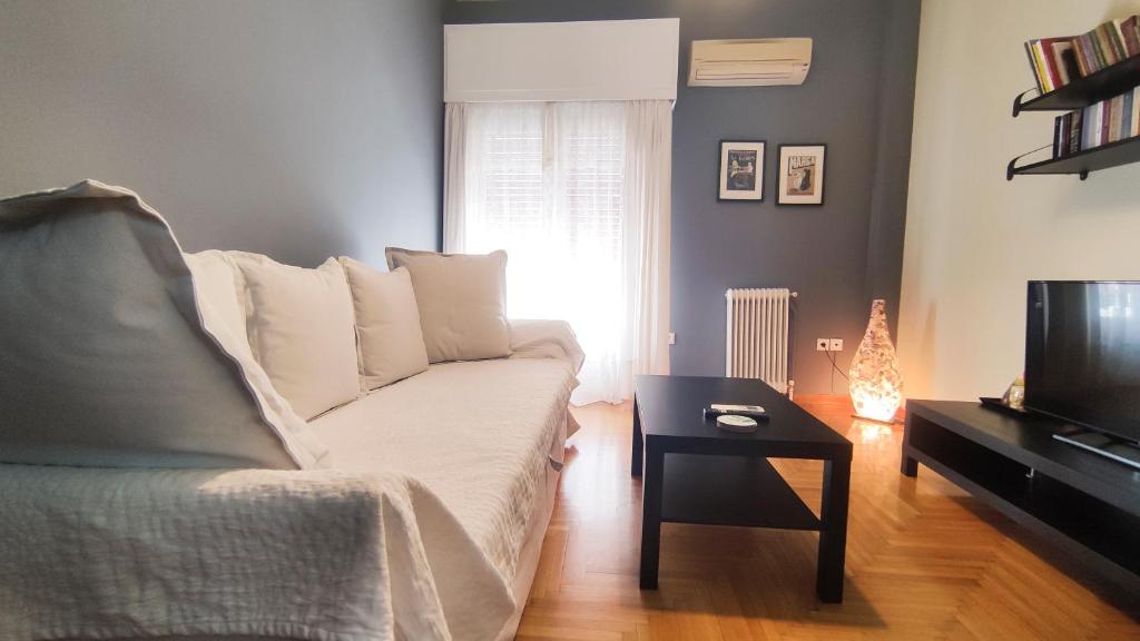 uma sala de estar com um sofá branco e uma televisão em Sandy's apartment em Nafplio