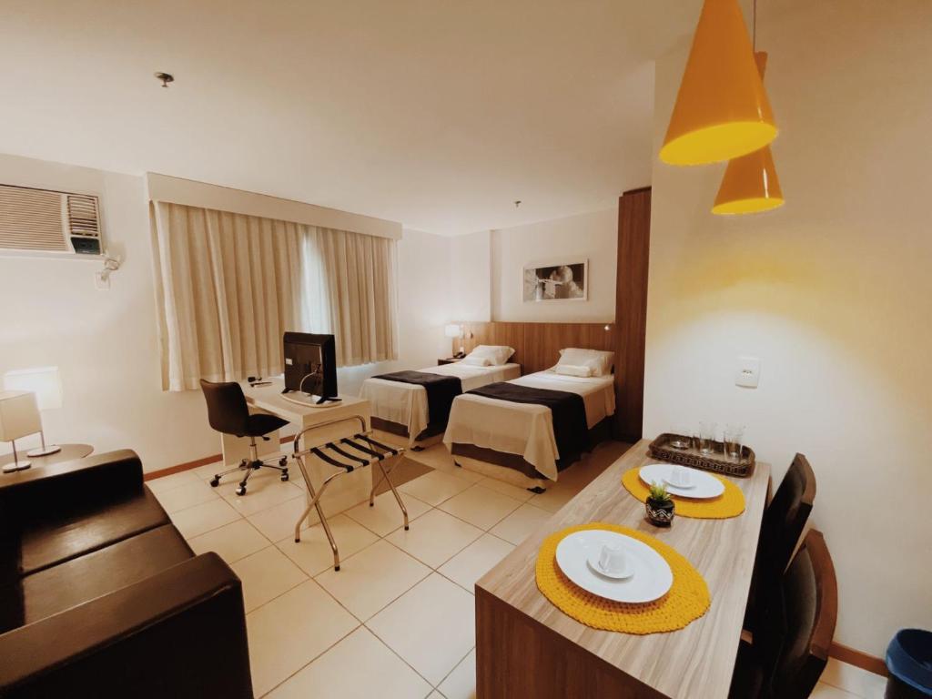 a hotel room with two beds and a dining table at Suíte completa no centro (SOHO Campos) in Campos dos Goytacazes