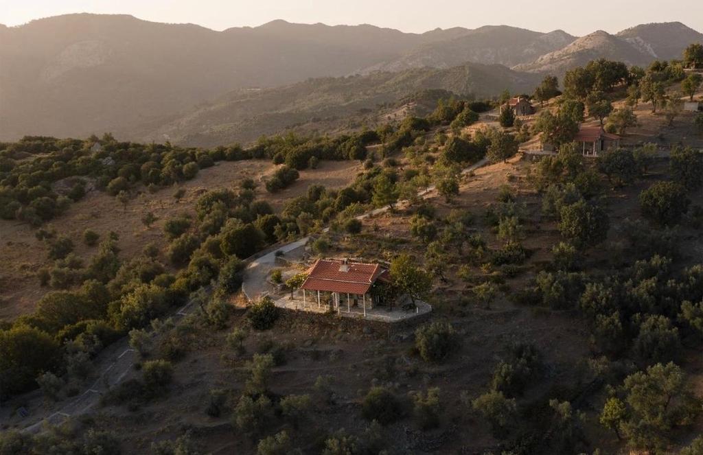 an aerial view of a house on a hill with a road at Toumba Eco Farm Guesthouses in Plomarion