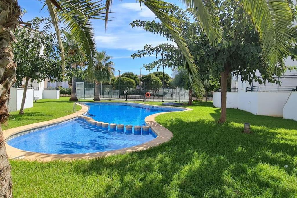 una piscina en un patio con palmeras en Bonrepòs Las Brisas apartamento planta baja en la playa en Alcocéber
