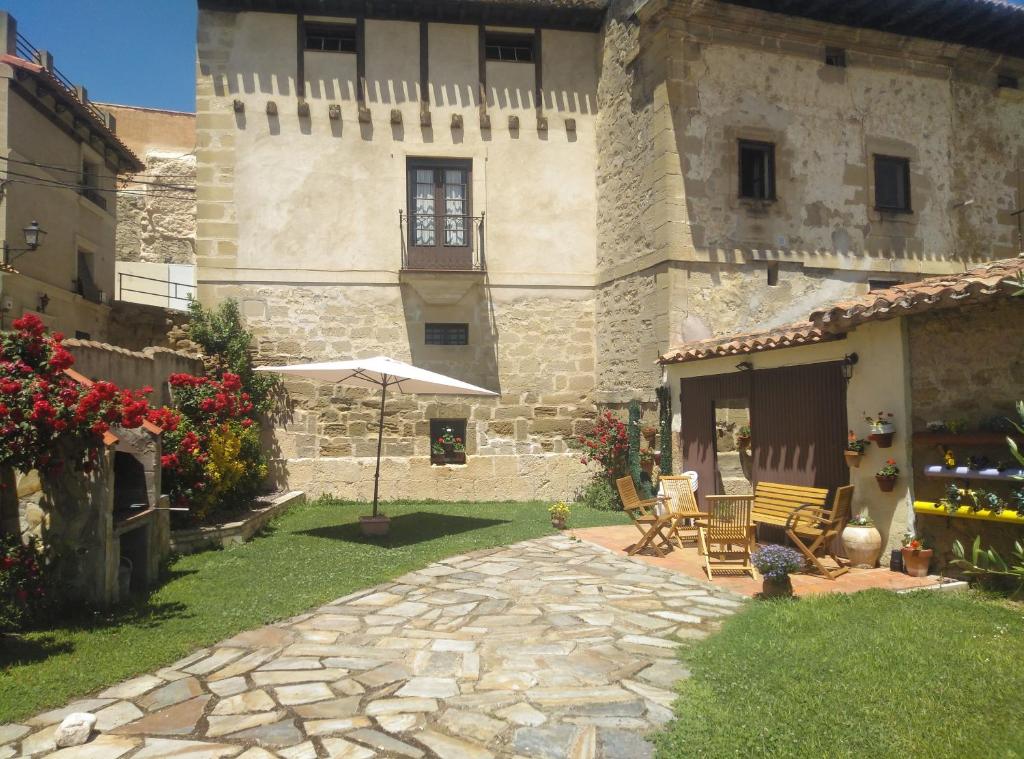 um grande edifício de pedra com um pátio com cadeiras e um guarda-sol em Casa Rural El Granero em Treviana