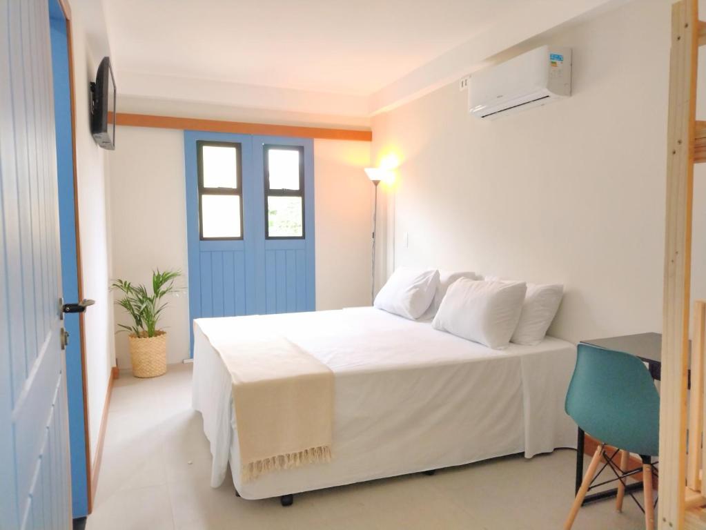 a bedroom with a white bed and a blue door at Pousada VilaZinha in Vila Velha