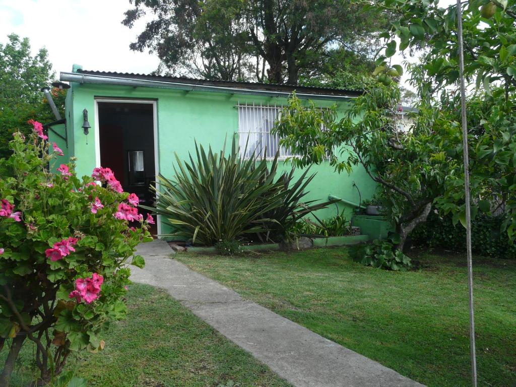 una casa verde con una puerta y algunas flores en El Jardin de Nora en Tandil