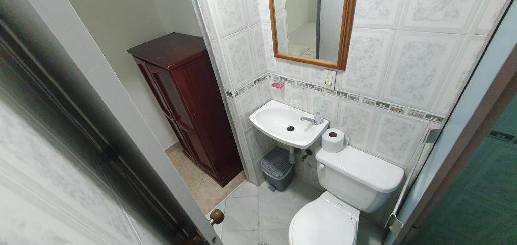 La salle de bains est pourvue de toilettes blanches et d'un lavabo. dans l'établissement Hotel Gran Imperio, à Medellín