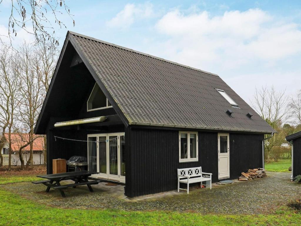 un edificio negro con una mesa de picnic delante en 5 person holiday home in Millinge, en Millinge