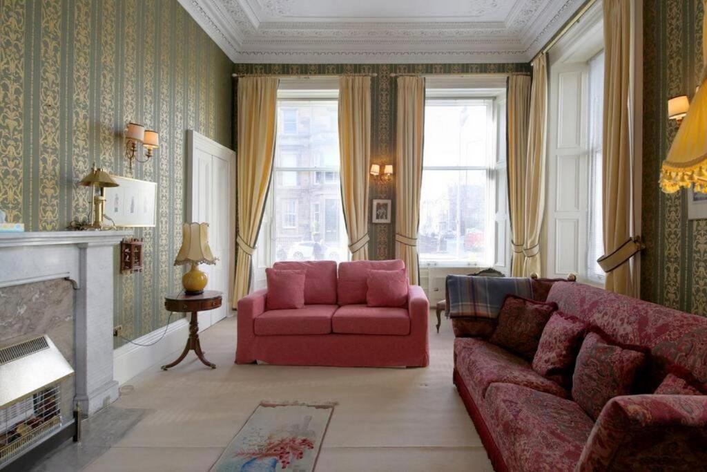ein Wohnzimmer mit einem rosa Sofa und einem Stuhl in der Unterkunft Quirky, West End, Edinburgh House in Edinburgh