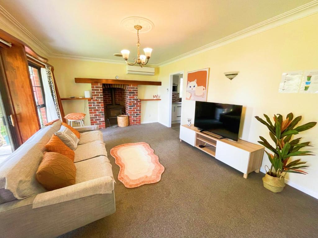 sala de estar con sofá y TV en Red sunny house en Rotorua
