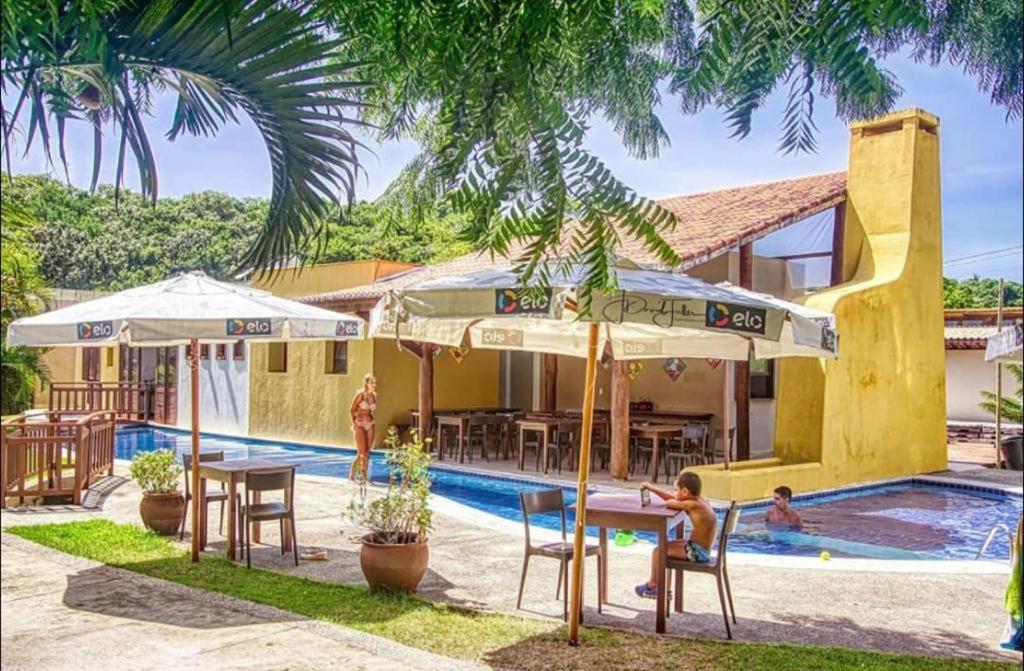 een resort met een zwembad met tafels en parasols bij Sol da Pipa Flats Bosque da Praia in Pipa