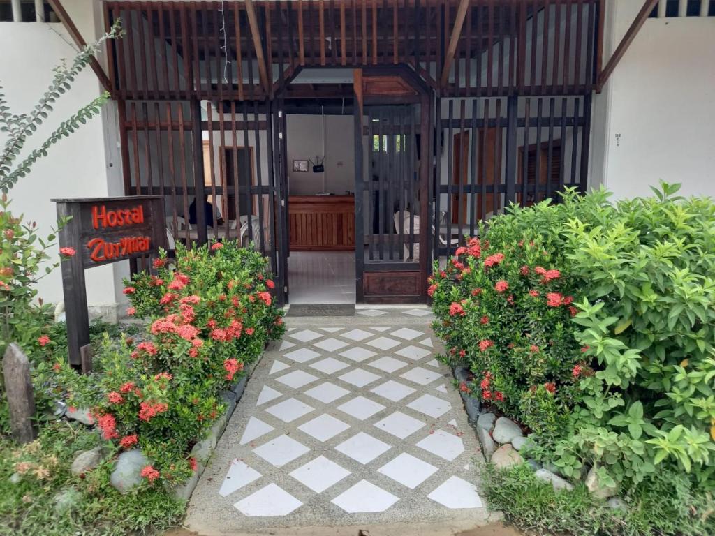 einen Eingang zu einem Haus mit Blumen und einem Schild in der Unterkunft Hostal Zurymar Capurganá in Capurganá