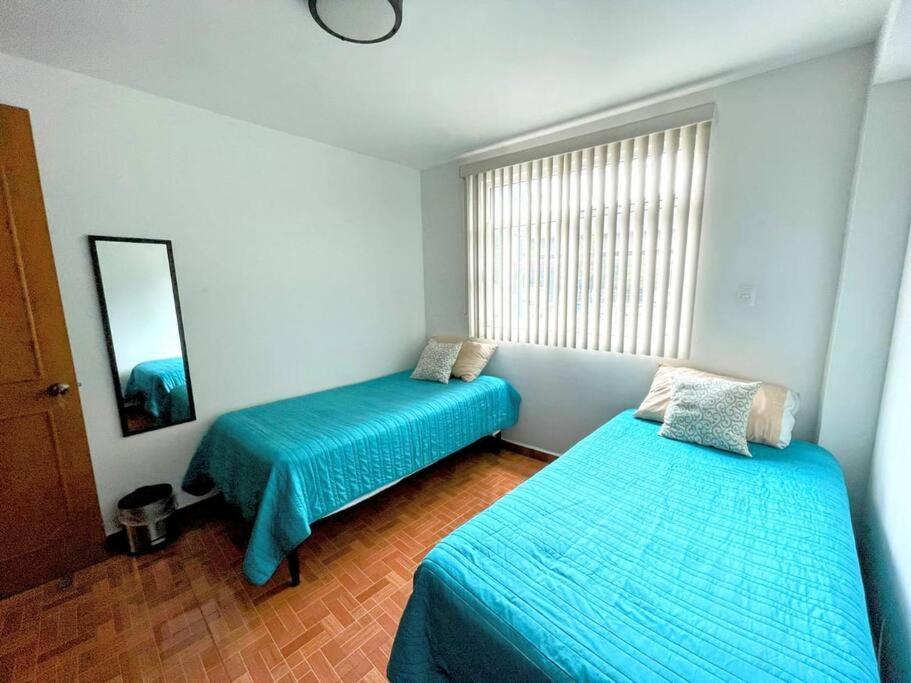 um quarto com duas camas e uma janela em DEPTO FRENTE AL AUTODROMO HMNOS A 10 MIN CAMINANDO em Cidade do México