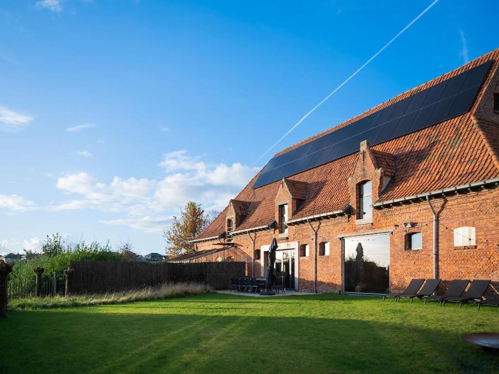 a large brick building with a solar roof at Cosy family home with pool in Moorslede