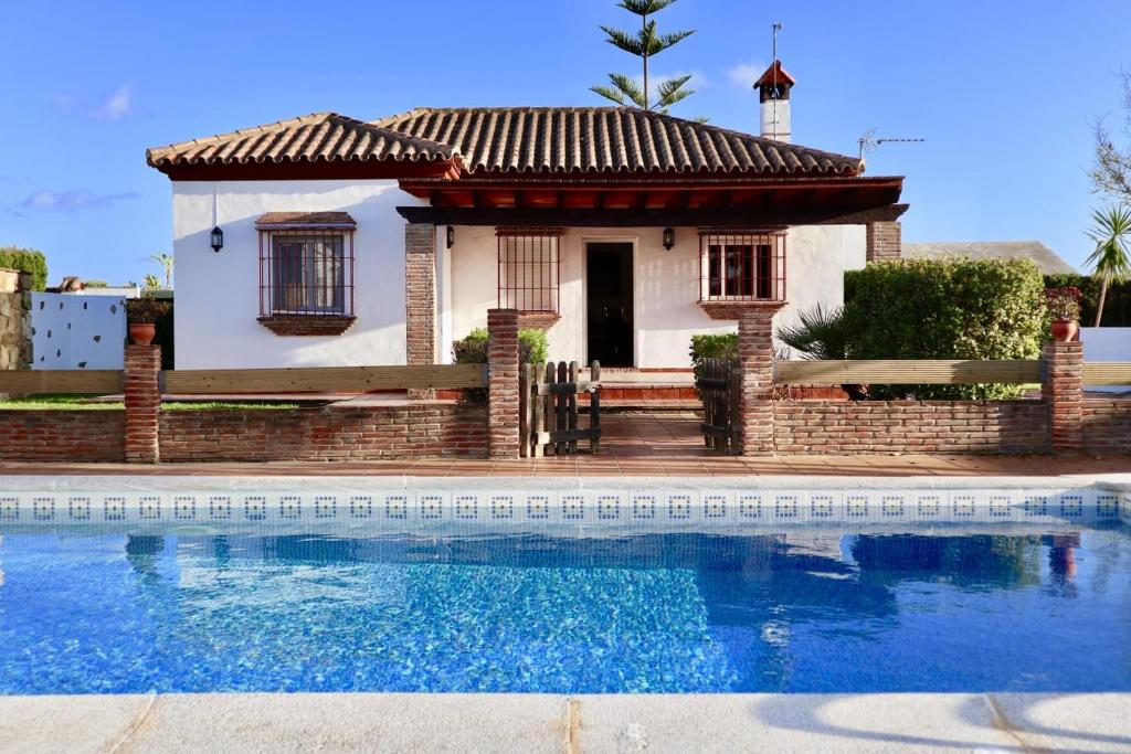 una pequeña casa con una piscina frente a ella en Fuente del Gallo Nomada, en Conil de la Frontera