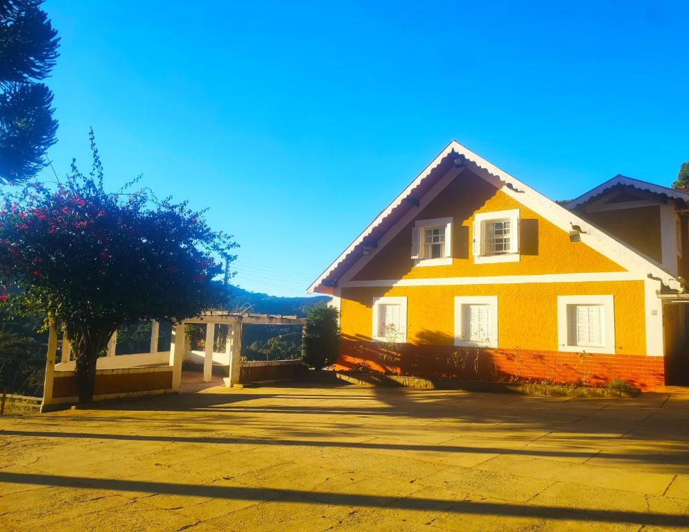 uma casa amarela ao lado de uma rua em Colônia SAA em Campos de Jordão