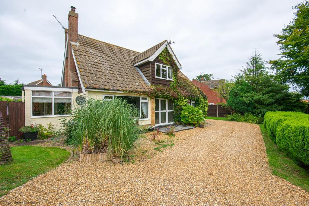 une maison avec une allée en gravier en face de celle-ci dans l'établissement Coastal cottage sleeping 10 with hot tub - 5 minutes to beach, à Bacton