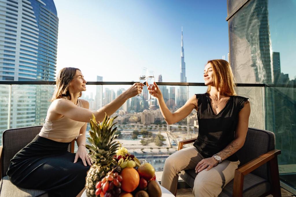 Duas mulheres a beber vinho no topo de um arranha-céus. em Ramee Dream Hotel Downtown em Dubai